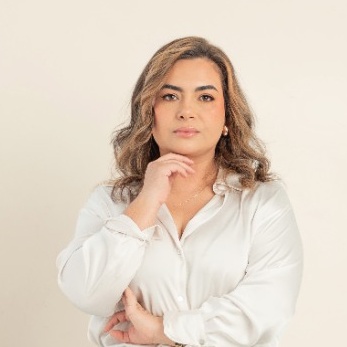 Bibiana Rojas, psicóloga, con blusa blanca y la mano en la barbilla.
